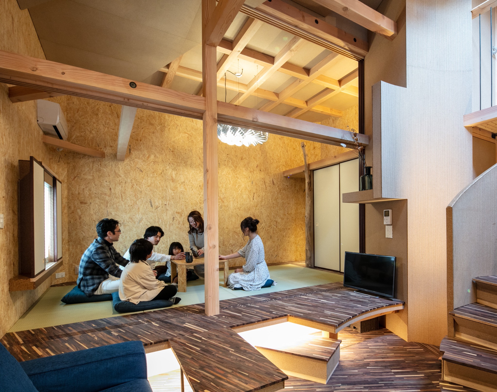 ARCHITEKTONの木造の室内。畳のスペースで、複数人がテーブルを囲んで過ごす様子。
